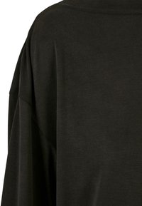 Schwarzes übergroßes Baumwoll-T-Shirt mit glatter Textur, lockeren Ärmeln und einfachem Rundhalsauschnitt.