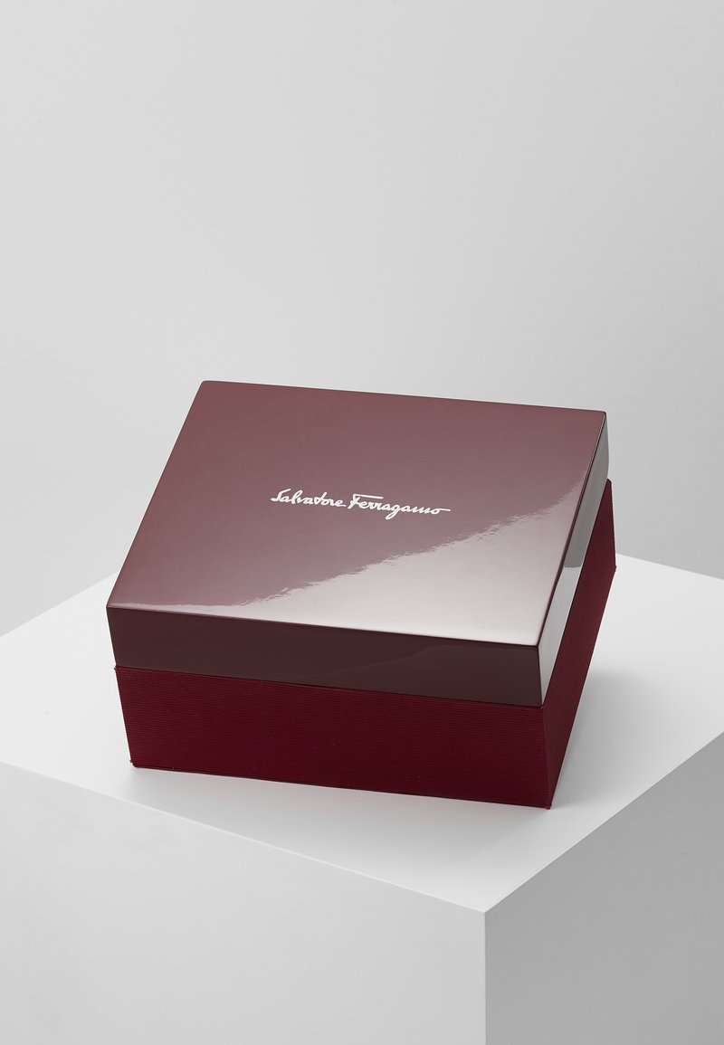 Boîte cadeau bordeaux avec un dessus brillant, présentant une base texturée mate et un logo en relief sur le couvercle. Forme rectangulaire, design minimaliste.