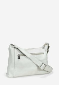 Bolso cruzado de cuero blanco con correa ajustable, presenta un bolsillo frontal con cremallera y una textura suave, diseño sencillo y herrajes metálicos.