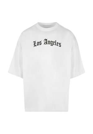 Fehér túlméretezett póló fekete Old English betűtípussal nyomtatva a mellkason, rajta a "Los Angeles" felirat.