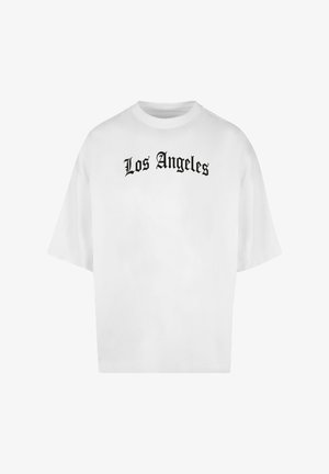 Fehér túlméretezett póló fekete Old English betűtípussal nyomtatva a mellkason, rajta a "Los Angeles" felirat.