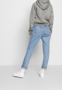 Gray glitter hoodie, light blue denim jeans with a relaxed fit, cuffed hems, and white sneakers with thick soles. Minimalist design and colors.