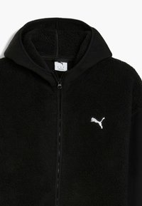 Schwarze Kapuzenjacke aus plüschigem Fleece. Verfügt über einen vollständigen Reißverschluss und ein weißes Puma-Logo auf der linken Brust. Glattes schwarzes Material an den Ärmeln.