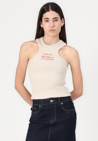 Beige geribde tanktop met een hoge hals, met uitgesneden schouderontwerp en rode tekst "REPLAY MonteCarlo Country Club". Draagt met donkere denim.