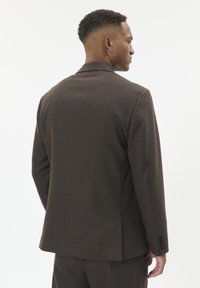 Brown tailored suit jacket, textured fabric, structured shoulders, single vent at the back, and buttoned cuffs. Back view shows overall fit and design.