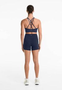 Marinblå sportbh med korsade axelband och matchande högmidjade shorts; tillverkad av ett smidigt, elastiskt material som passar för aktiv klädsel.
