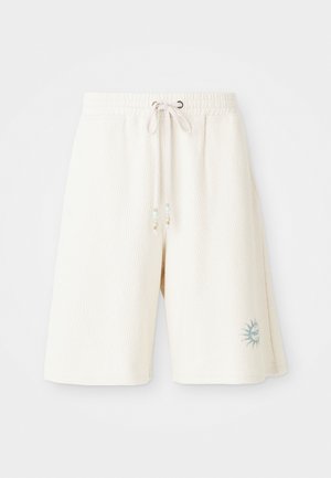 Light cream shorts made of textured fabric with an elastic waistband, adjustable drawstring, and a printed sun design on the left leg.