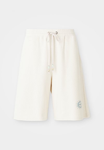 Lys kremfargede shorts laget av strukturert stoff med elastisk midje, justerbar snor og et trykt solmotiv på venstre ben.