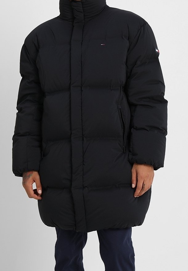 Giubbotto imbottito nero con collo alto, sezioni trapuntate per l'isolamento, tasche laterali con cerniera e dettaglio logo sul petto.