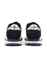 Een paar marineblauwe en witte sneakers met zwarte zolen, van achteren gezien, met "SUN68" branding op zilverkleurige hiel-tabs.