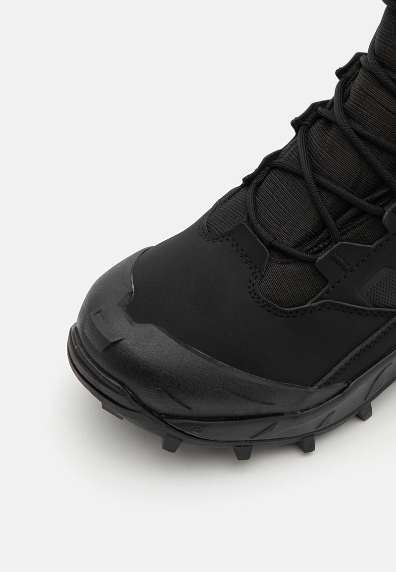 Stivale da trekking nero con una suola in gomma testurizzata, punta rinforzata e parte superiore in tessuto. Presenta un sistema di allacciatura per una vestibilità aderente.