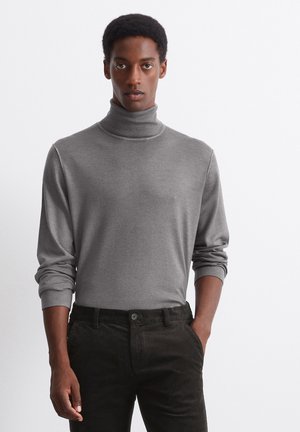 Gray turtleneck sweater made of soft fabric, featuring long sleeves and a fitted design. Paired with black corduroy pants.