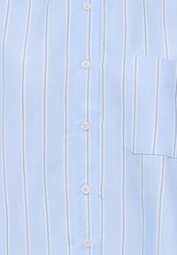 Chemise bleu clair avec des rayures blanches verticales, des boutons blancs sur le devant et une poche sur le côté gauche.