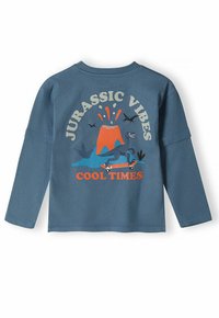 Hosszú ujjú, puha anyagú kék ing, vulkáni grafikával, dinoszaurusszal és narancssárga szöveggel: "Jurassic Vibes Cool Times".