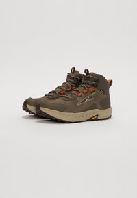 Mørke olivengrønne tursko med beige såle, teksturert overdel, oransje detaljer og forsterket ankle støtte. Har slitesterke snorer og godt grep.