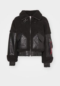 Schwarze cropped Jacke mit Fleece-Korpus und Lederärmeln. Verfügt über einen Reißverschluss, zwei Fronttaschen und elastische Bündchen. Einschließlich eines roten Etiketten-Details.