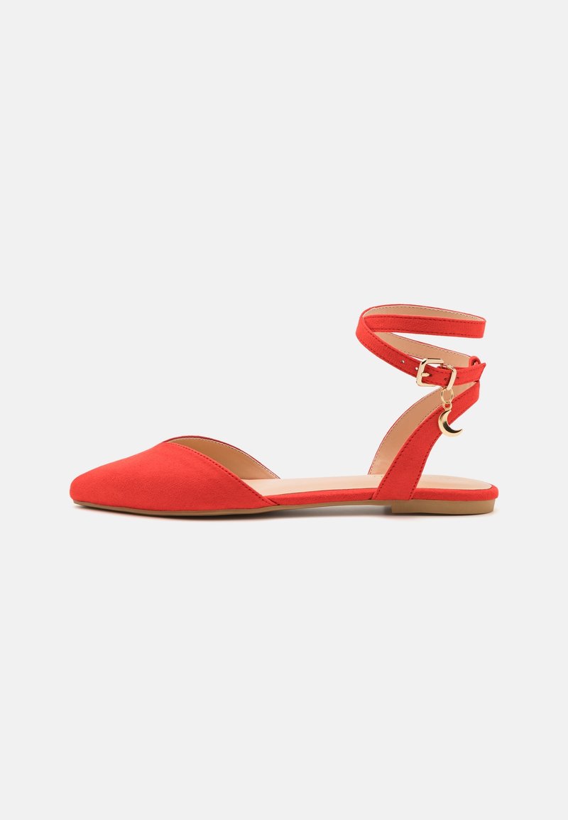 Chaussure plate rouge à bout pointu, bride de cheville avec petite boucle dorée et pendentif croissant de lune suspendu à la bride.