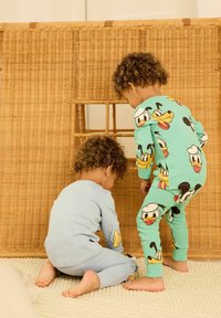 Peutermode: één in lichtblauw met cartoonfiguren, één in groen met kleurrijke prints. Zachte katoenen stof, lange mouwen en broekspijpen.