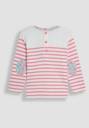 Stribet skjorte med lange ærmer i hvid og pink, med blomsterlapper ved albuerne og en knaplukning på ryggen med pink knapper. Blødt stof.