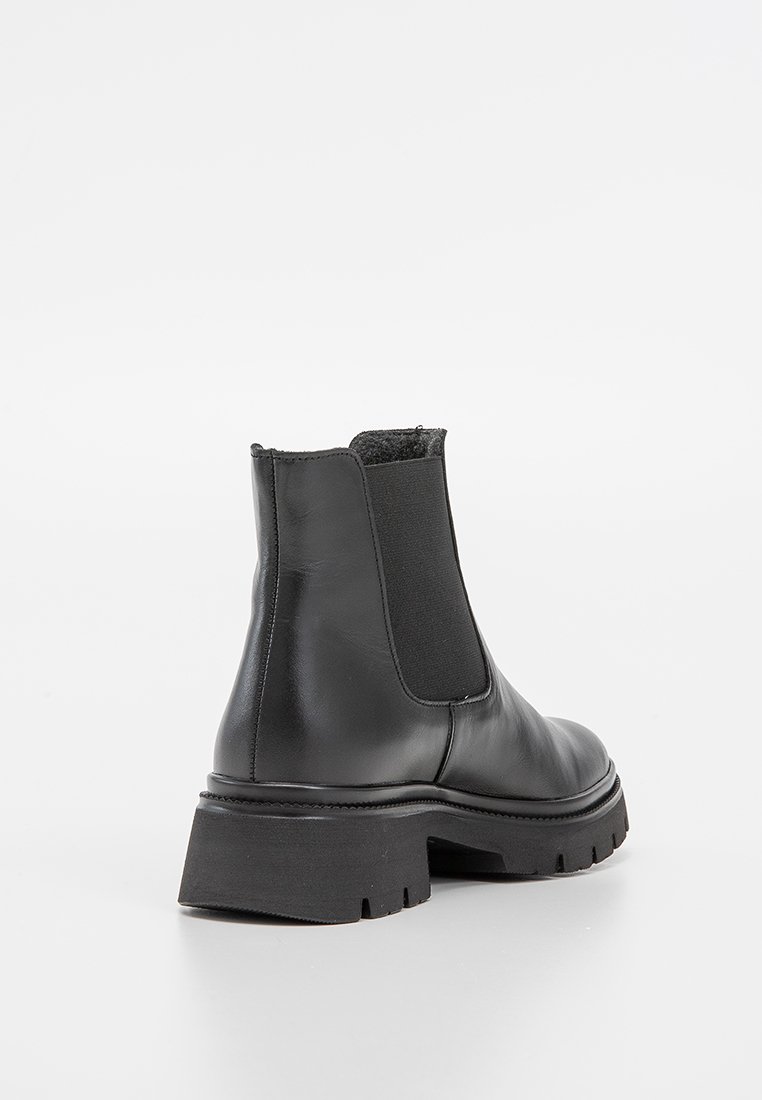 Botas Chelsea de cuero negro con paneles elásticos laterales y una suela de goma texturizada y resistente. Upper suave con punta redondeada y un diseño minimalista.