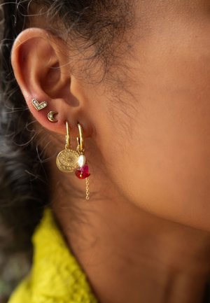 Orecchini a cerchio in oro con un ciondolo a forma di moneta arricchito da perline rosse e rosa, completati da piccoli orecchini a forma di cuore e di luna in argento.