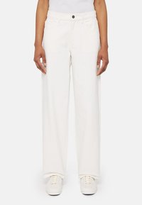 Pantalones de algodón blancos de pernera ancha con cierre de botón, bolsillos frontales y una textura suave, combinados con zapatillas blancas.