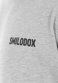 Grå bomulds t-shirt med et iøjnefaldende sort "SMILODOX" logo foran, tekstureret stoffinish og rund hals design.