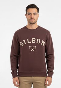 Sudadera marrón con bordado en beige de "SILBON" y diseño de raqueta de tenis. Presenta puños y dobladillo de canalé, fabricada en un suave tejido texturizado.