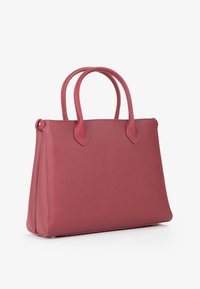 Borsa a mano strutturata in pelle rossa con doppi manici e una finitura testurizzata, posata su una superficie bianca.