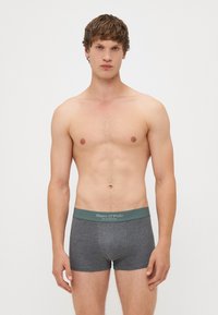 Shorts de boxe gris avec une taille de couleur vert clair arborant la marque "Marc O'Polo." Texture douce et design ajusté, adaptés pour une utilisation active.
