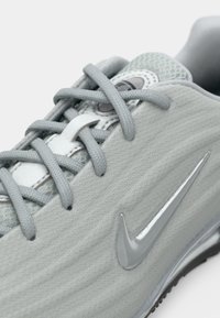 Heled hallid spordijalatsid puuvillasevõrguga, hallid paelad ja läikiv hall Nike logo küljel.