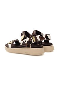 Cowhide sandals with adjustable straps, featuring a brown and white spotted pattern, a cushioned insole, and a beige platform sole.