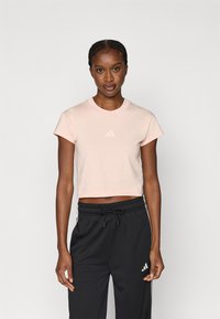 Ροζ ανοιχτό ροζ cropped t-shirt με στρογγυλή λαιμόκοψη και κοντά μανίκια, με διακριτικό λευκό λογότυπο Adidas στο στήθος. Μαύρο φαρδύ παντελόνι.