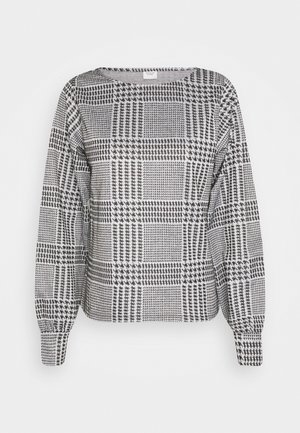 Blouse à manches longues à carreaux pied-de-poule noir et blanc avec encolure arrondie et manches avec poignets.