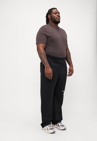 Gray short-sleeve t-shirt and black sweatpants. Pants feature an elastic waistband; shoes are gray with white accents. Flat, smooth fabric texture.