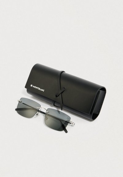 Óculos de sol com armação de metal prateado e lentes cinzentas degradê, colocados ao lado de um estojo de couro preto, com um logótipo e atado com uma correia.