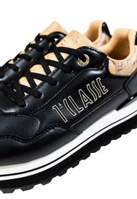 Zapatillas de cuero negro con detalles en color tan, cordones negros, raya blanca en la suela y la marca "1ª CLASSE" en el lado.