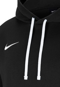 Hoodie noir avec cordon de serrage, doté de cordons blancs et d'un petit logo Nike swoosh blanc sur le devant. Texture de tissu douce.