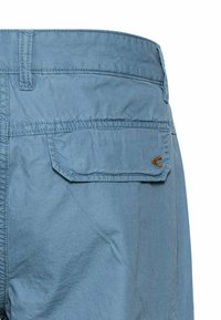 Light blue shorts made of lightweight fabric with a textured finish. Features back pockets and subtle stitching details.