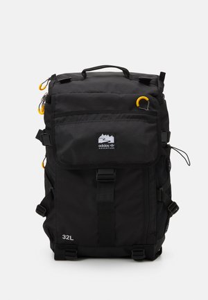 Sac à dos noir Adidas Adventure 32L avec plusieurs compartiments, tirettes de fermeture éclair jaunes, poches latérales en mesh et poignée supérieure.