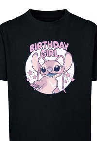 Sort bomulds T-shirt med et pink grafik af en karakter med store ører, mærket "FØDSELSDAGSPIGE," omgivet af stjerner i et cirkulært design.