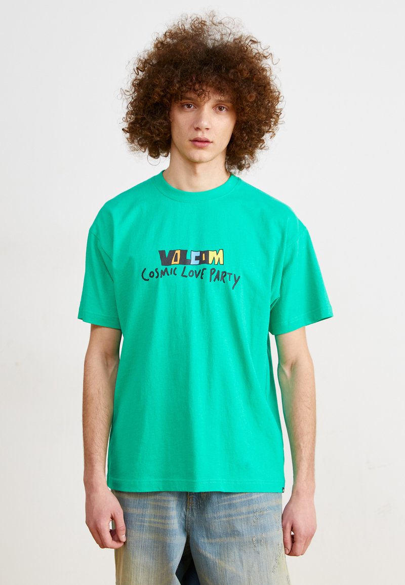 Turquoise cotton t-shirt featuring a graphic print with "VOLCOM COSMIC LOVE PARTY" in bold, contrasting colors. Short sleeves, crew neckline.
