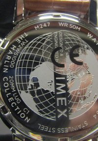 Zegarek Timex ze stali nierdzewnej z wzorem globu na tylnej części. Zawiera napisy "Timex", "Kolekcja Marlon" oraz "WR 50M". Widoczny brązowy skórzany pasek.