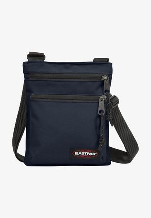 Granatowa torba na ramię z dwoma kieszeniami na suwak, regulowanym czarnym paskiem i naszywką z logo Eastpak na przedniej kieszeni.