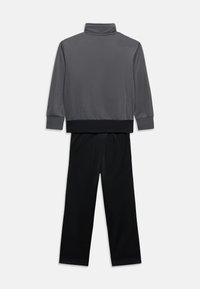 Γκρι μπλούζα μακρυμάνικη με μαύρη ζώνη στη μέση, συνδυασμένη με μαύρο παντελόνι ίσιας γραμμής, εμφανίζεται επίπεδη σε λευκό φόντο.