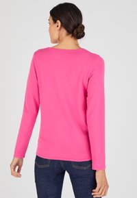 Roze lange mouwen trui in zachte gebreide stof met een ronde halslijn, rechte snit en een gladde textuur, gecombineerd met donkerblauwe spijkerbroek.