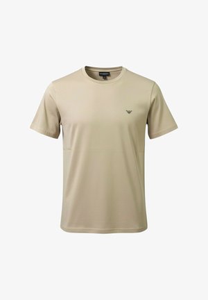 T-shirt beige a maniche corte con scollo rotondo e piccolo logo nero sul petto a sinistra, mostrata su sfondo bianco semplice.