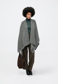 Grå ullblandings omslag med åpen front, kombinert med en grønn høyhalset genser, brune brede bukser og en brun semsket skinnveske.