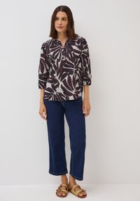 Långärmad skjorta med krage i ljusgrått med mörkröd bladmönster, kombinerad med mörkblå korta jeans och tanfärgade flätade sandaler.