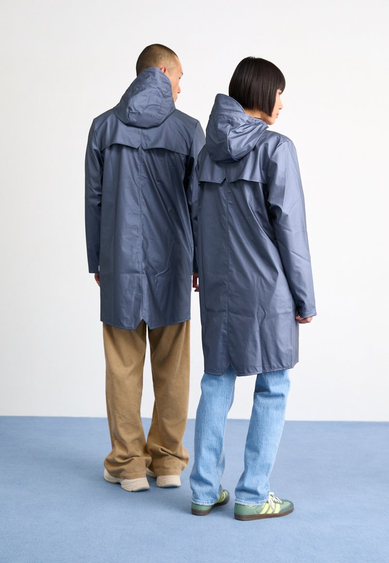 Unisex, long, hooded raincoat in dark gray, made from water-resistant material. Features a back yoke and side pockets.